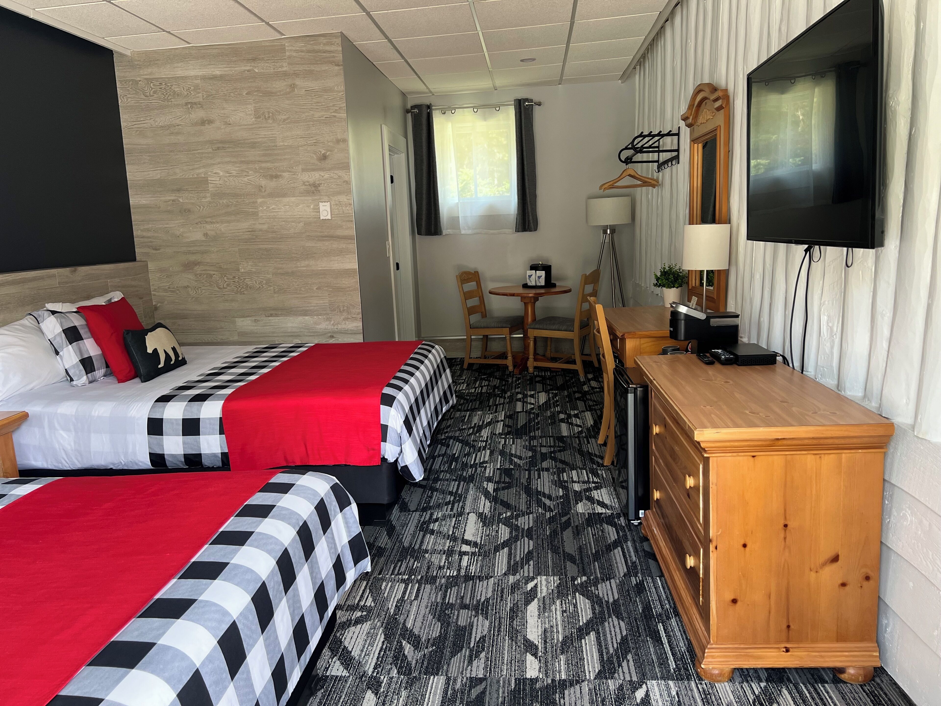 Ett hotellrum med två sängar, ett skrivbord i trä, en tv och ett matbord.