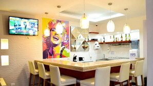 A modern kitchen with a bar area, bar stools, and a television mounted on the wall. - Hotel La Riviera (Santa Marta)