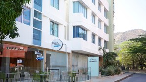 A hotel with outdoor seating, a sign for 'Oceano Azul', and a view of a hilly landscape. - Hotel La Riviera (Santa Marta)