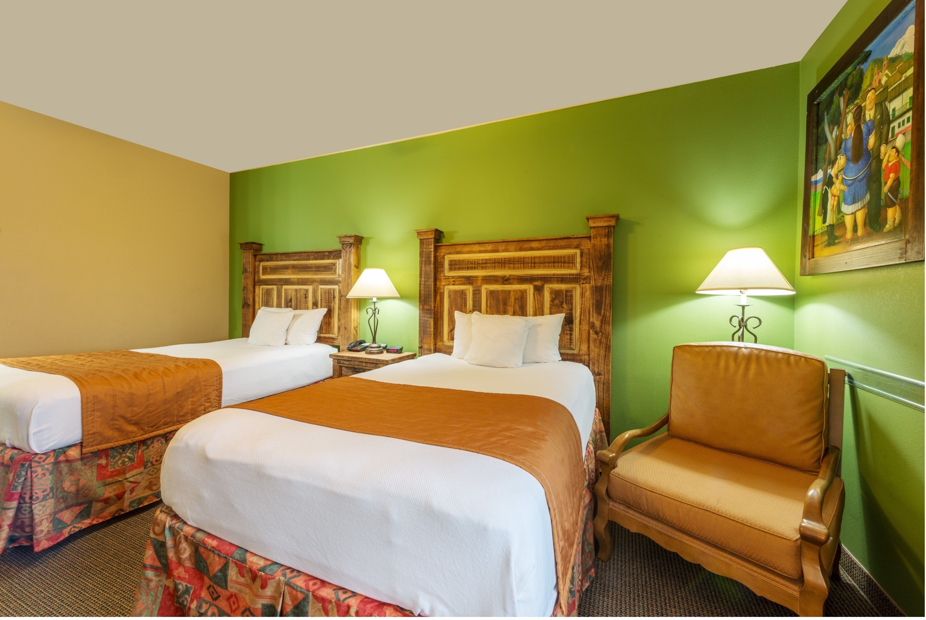A hotel room with two beds, a chair, and a painting on the wall.