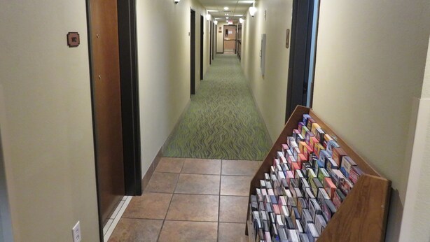 Un pasillo de hotel con alfombra verde, una zona de máquinas expendedoras y un letrero de salida.