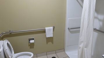 Een badkamer met toilet, een handgreep, een douchegordijn en een betegelde vloer.