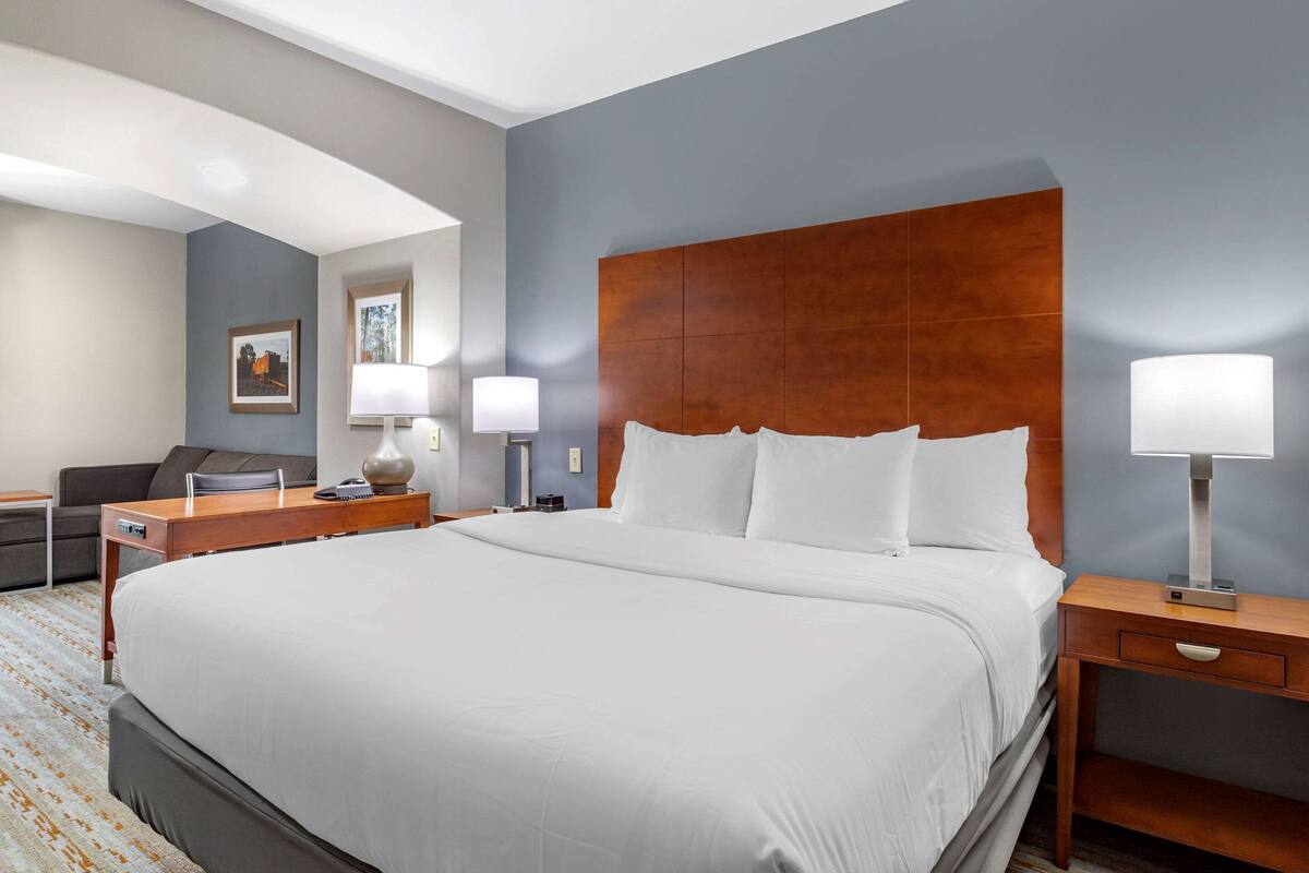 Une chambre d’hôtel avec un grand lit, un bureau, une chaise et deux lampes de chevet.
