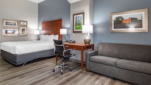 A hotel room with a bed, desk, chair, and sofa. - Comfort Inn & Suites Cleveland TX (Cleveland)