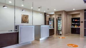 A modern hotel lobby with a reception desk, a refrigerator stocked with beverages, and a snack bar. - Comfort Inn & Suites Cleveland TX (Cleveland)
