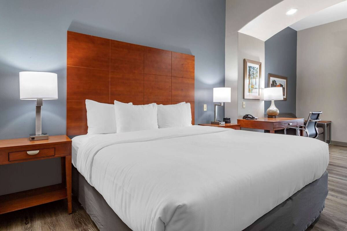 Une chambre d’hôtel avec un grand lit, un bureau, deux tables de chevet et une chaise.
