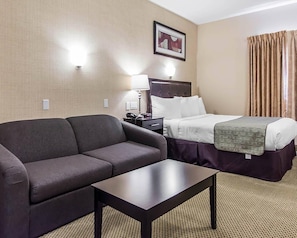 Una habitación de hotel con cama, sofá, mesa y lámpara.