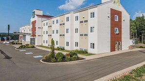 A modern multi-story hotel with a parking lot in front. - Quality Inn (Moncton)