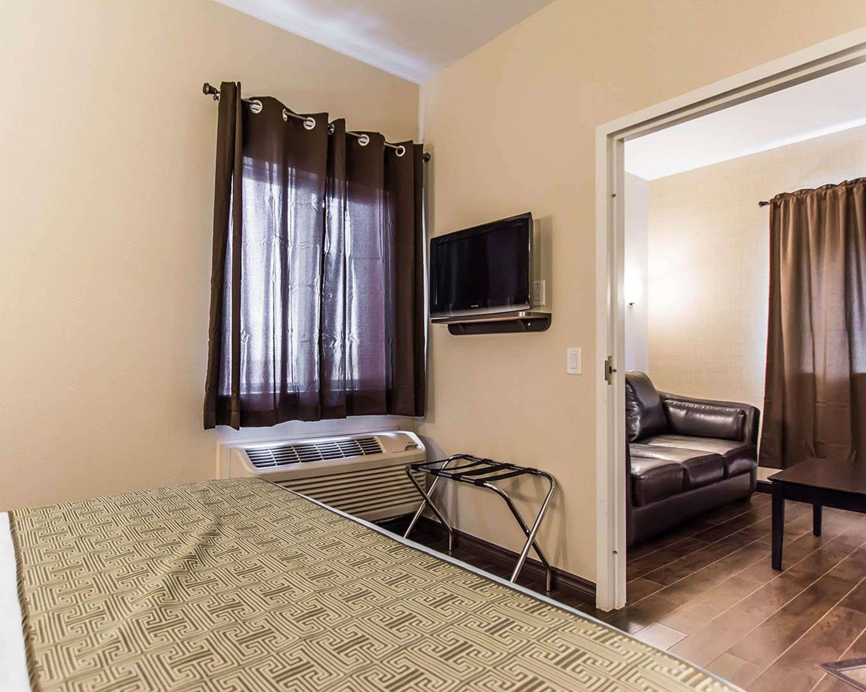 Un ambiente compatto con un letto, una TV a parete, un divano e un tavolo da pranzo.