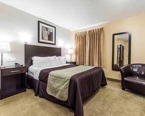 A hotel room with a bed, bedside tables, a lamp, a chair, and a mirror.