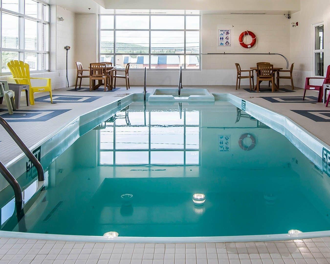 An indoor swimming pool with a clear view of the outside through large windows.