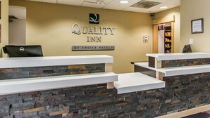 A reception area with a stone facade, a Dell computer, and a sign for Quality Inn by Choice Hotels. - Quality Inn (Moncton)