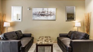 A living room with two leather sofas, a coffee table, and two wall-mounted lamps. - Quality Inn (Moncton)