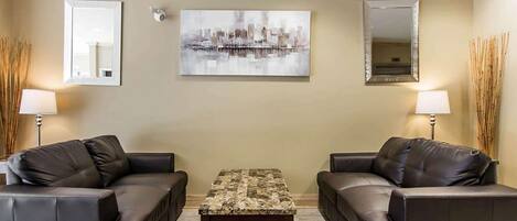 Un salon avec deux canapés en cuir, une table basse et deux lampes fixées au mur.
