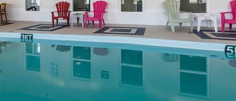 A swimming pool with chairs and signs indicating pool rules.