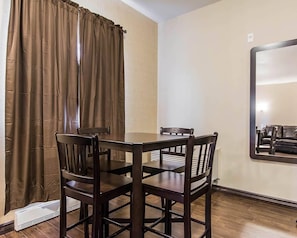 Un comedor con una mesa y sillas, una ventana con cortinas y un espejo montado en la pared.