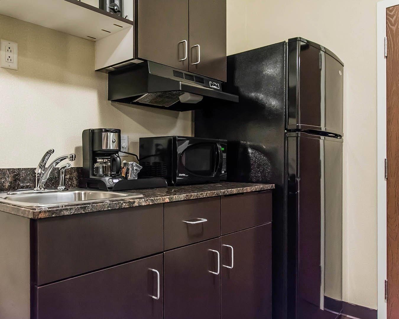 A kitchen with a stainless steel sink, a coffee maker, a microwave, and a refrigerator.