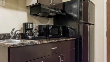 A kitchen with a stainless steel sink, a coffee maker, a microwave, and a refrigerator.
