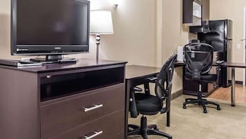 A hotel room with a desk, a television, a chair, and a cabinet.