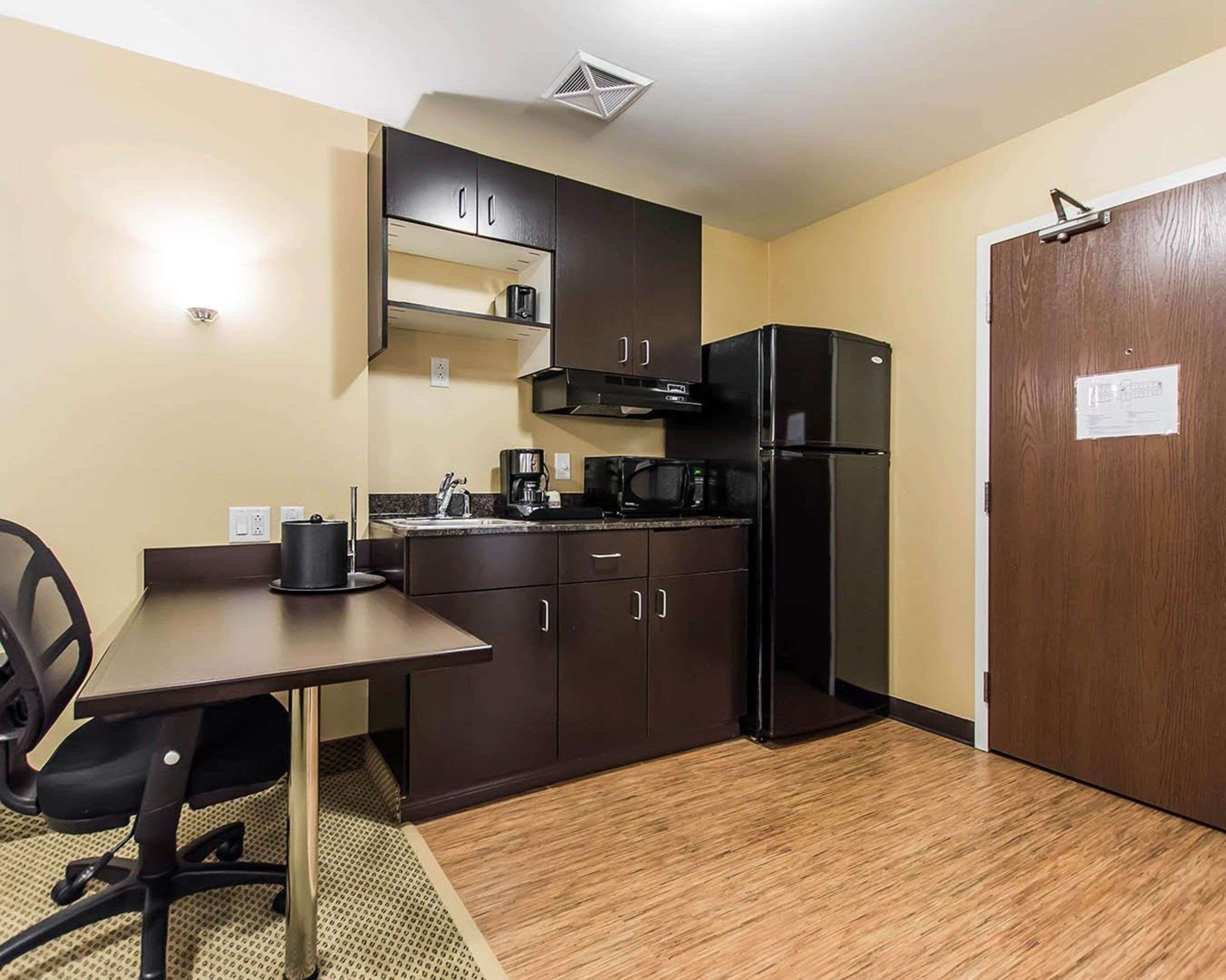 A compact kitchen with dark cabinets, a black refrigerator, a microwave, and a coffee maker.