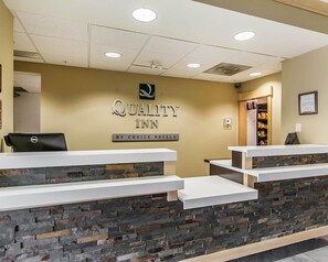 A reception desk with a stone facade, a sign reading 'Quality Inn by Choice Hotels,' and a Dell computer on the left. - Quality Inn Moncton North (Moncton)
