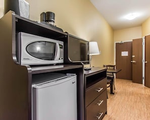 A compact kitchenette with a microwave, refrigerator, and a small table with a lamp. - Quality Inn Moncton North (Moncton)