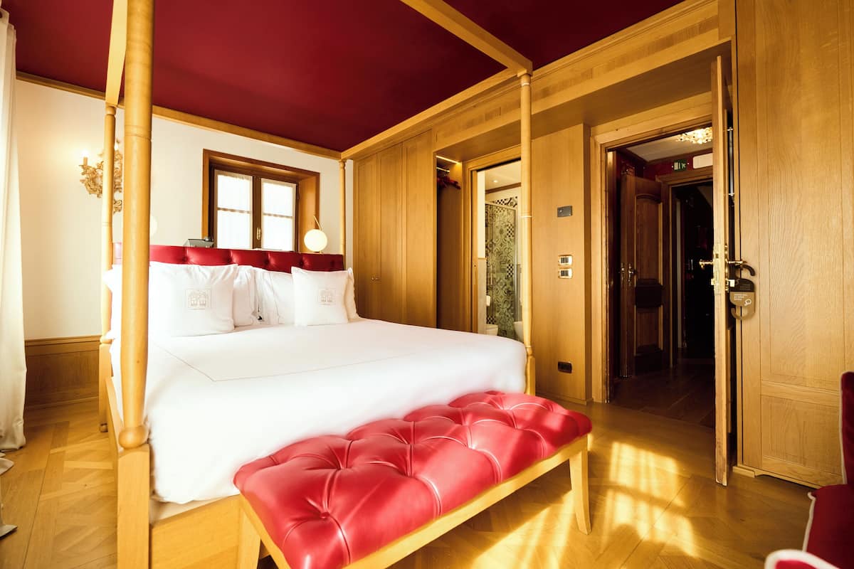Une chambre avec un grand lit, des murs en bois, un plafond rouge et un banc rouge.