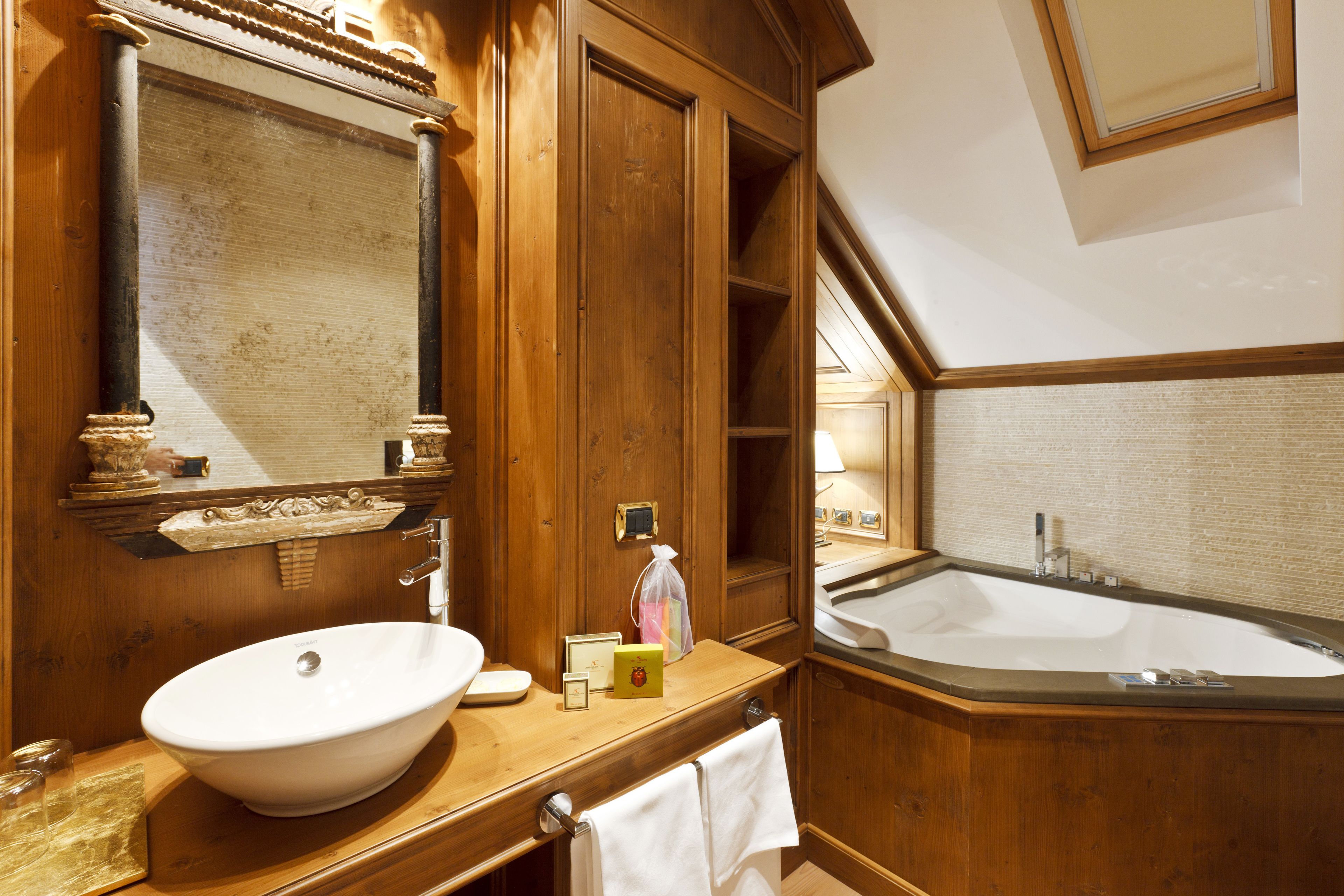 A wooden bathroom with a large oval sink, a mirror, and a freestanding bathtub.