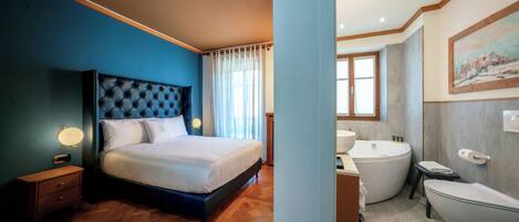 A bedroom with a large bed, a nightstand, and a bathroom with a bathtub, toilet, and sink.