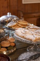 Ein Buffet mit verschiedenen Backwaren, darunter Gebäck und Brot, präsentiert auf Metallservierplatten.