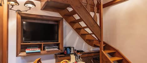 A wooden staircase with a built-in desk and chair, a window above, and a television on the wall.