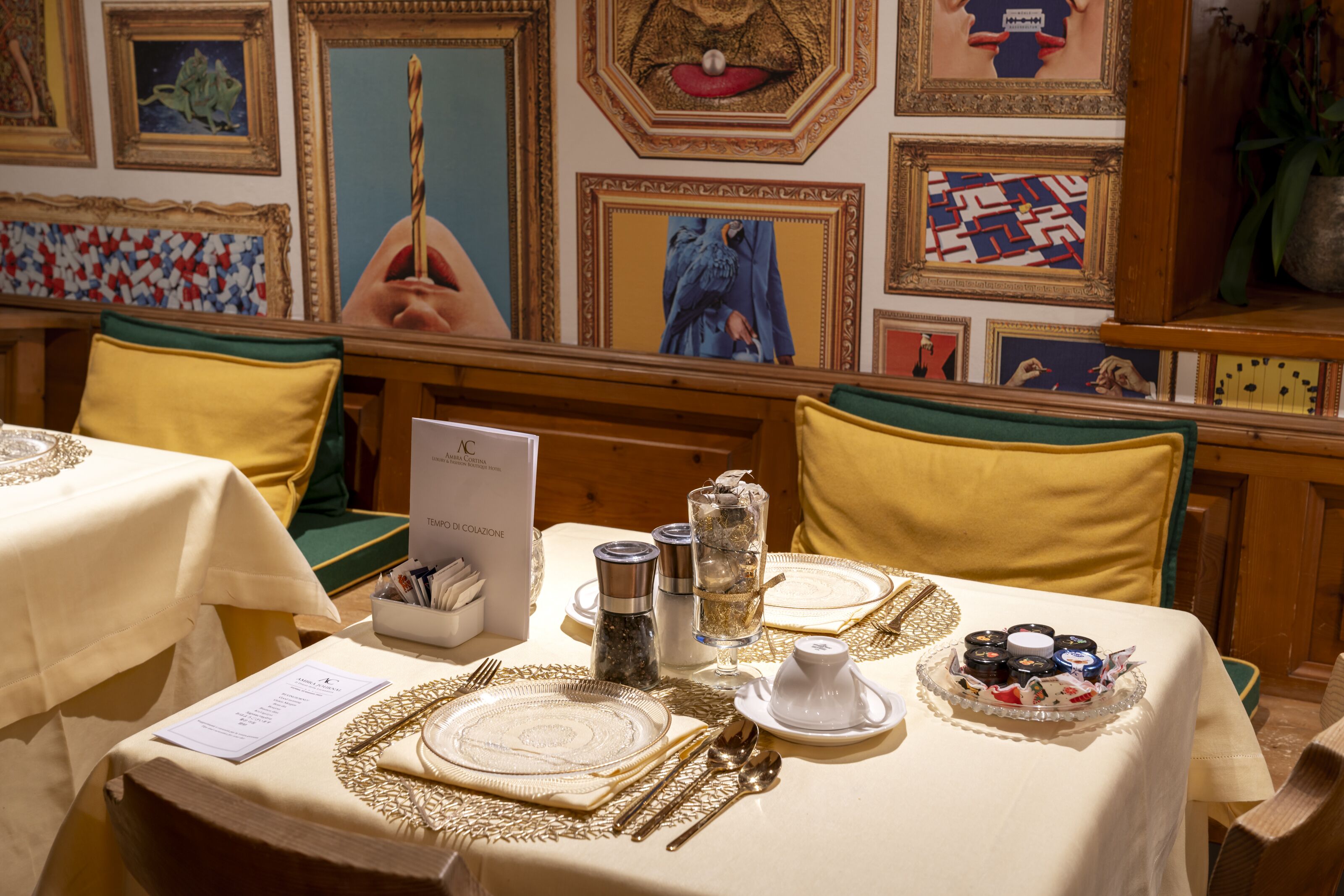 Una mesa de comedor dispuesta con vajilla de porcelana, cubiertos y un plato de postre, rodeada de sillas amarillas con cojines verdes.