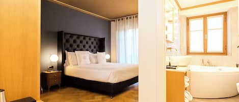 A hotel room with a bed, bedside table, lamp, and a bathroom with a bathtub and sink.