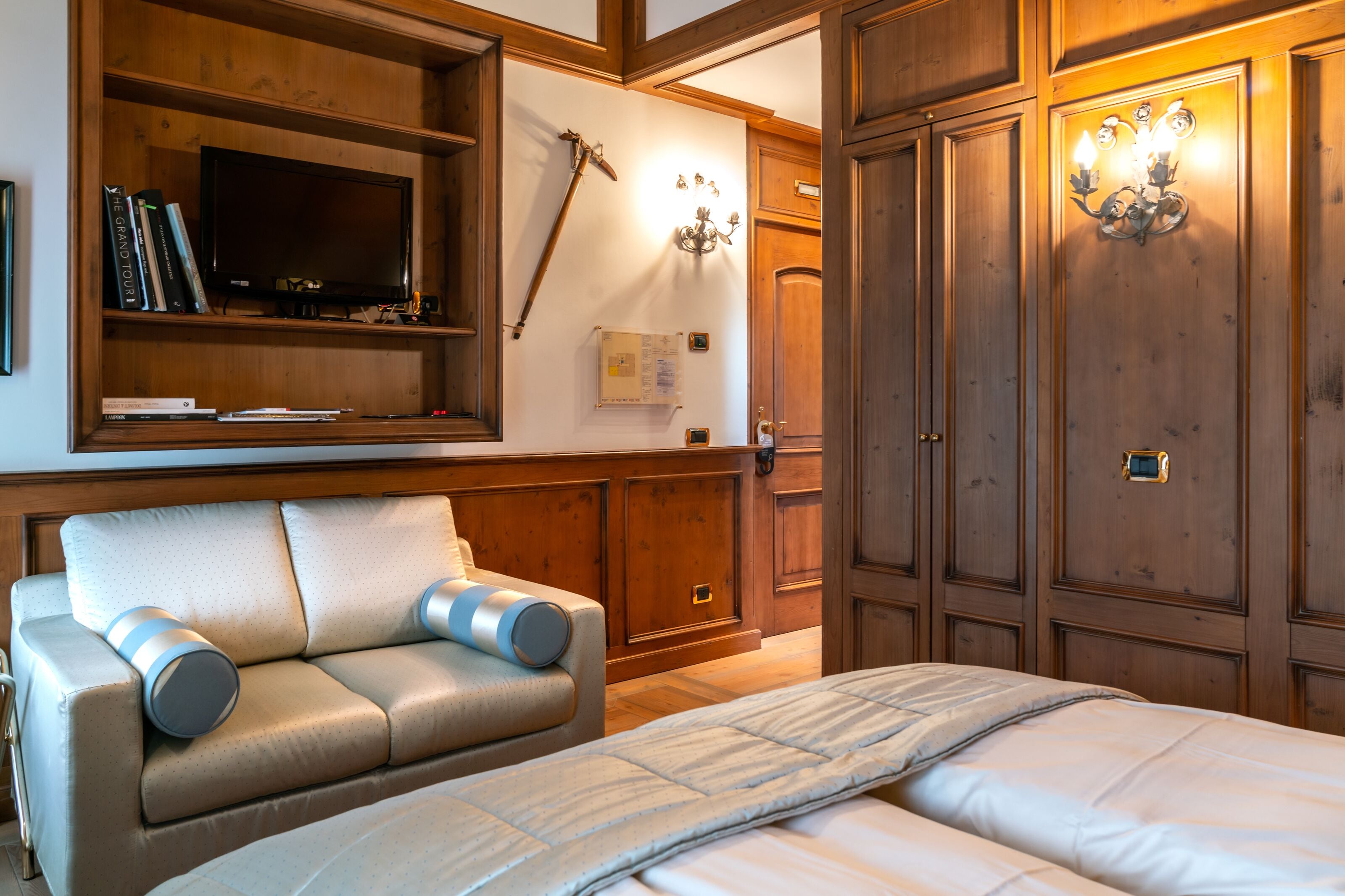 Camera da letto con un letto, un divano, una TV, mobili in legno e applique.
