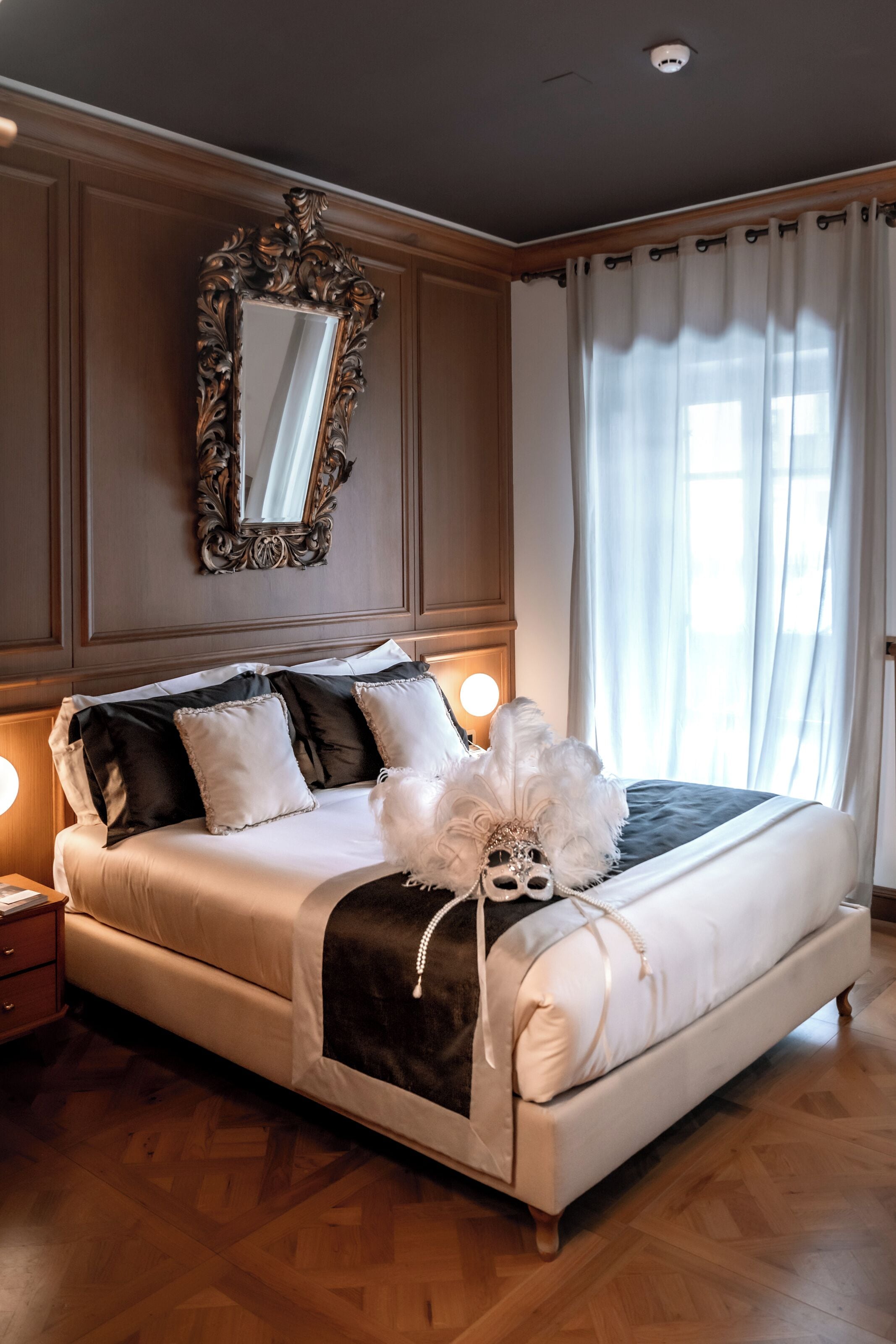 A bedroom with a large bed, a mirror, and a nightstand.