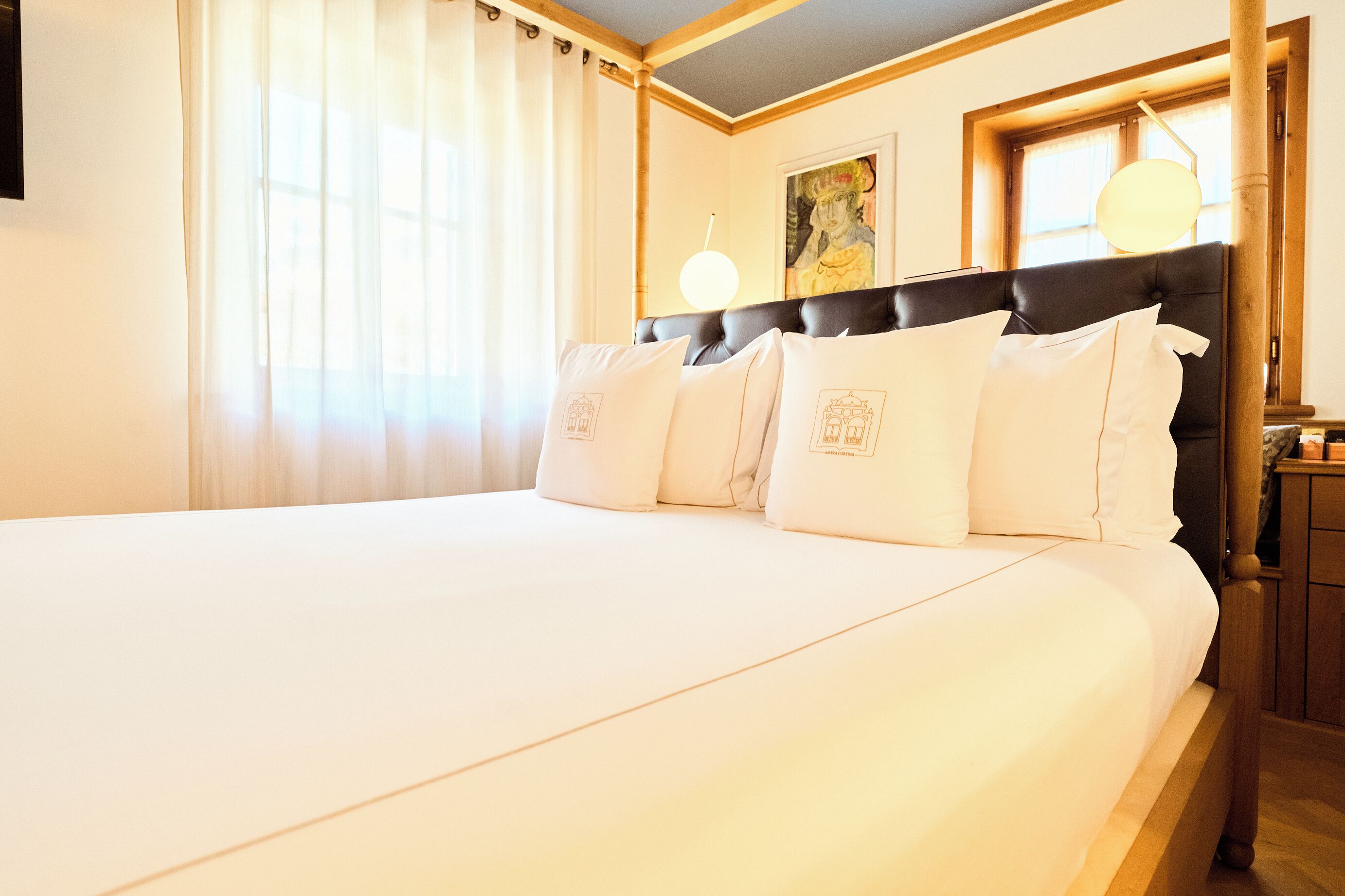Une chambre d’hôtel avec un grand lit, une tête de lit, un tableau au mur et une table de chevet avec une lampe.