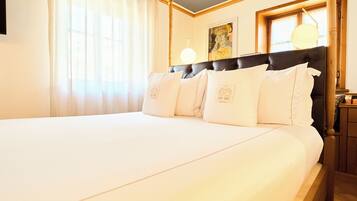 Une chambre d’hôtel avec un grand lit, une tête de lit, un tableau au mur et une table de chevet avec une lampe.