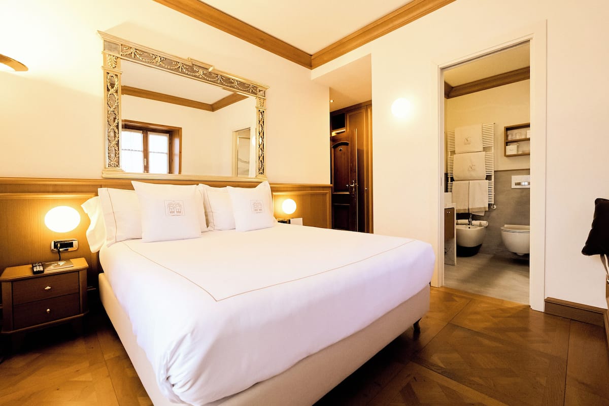 Une chambre d’hôtel avec un grand lit, une table de chevet avec un téléphone, un miroir et une vue sur la salle de bain.