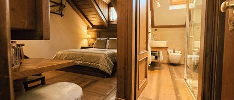 Een slaapkamer met een bed, nachtkastje, stoel en houten vloer.