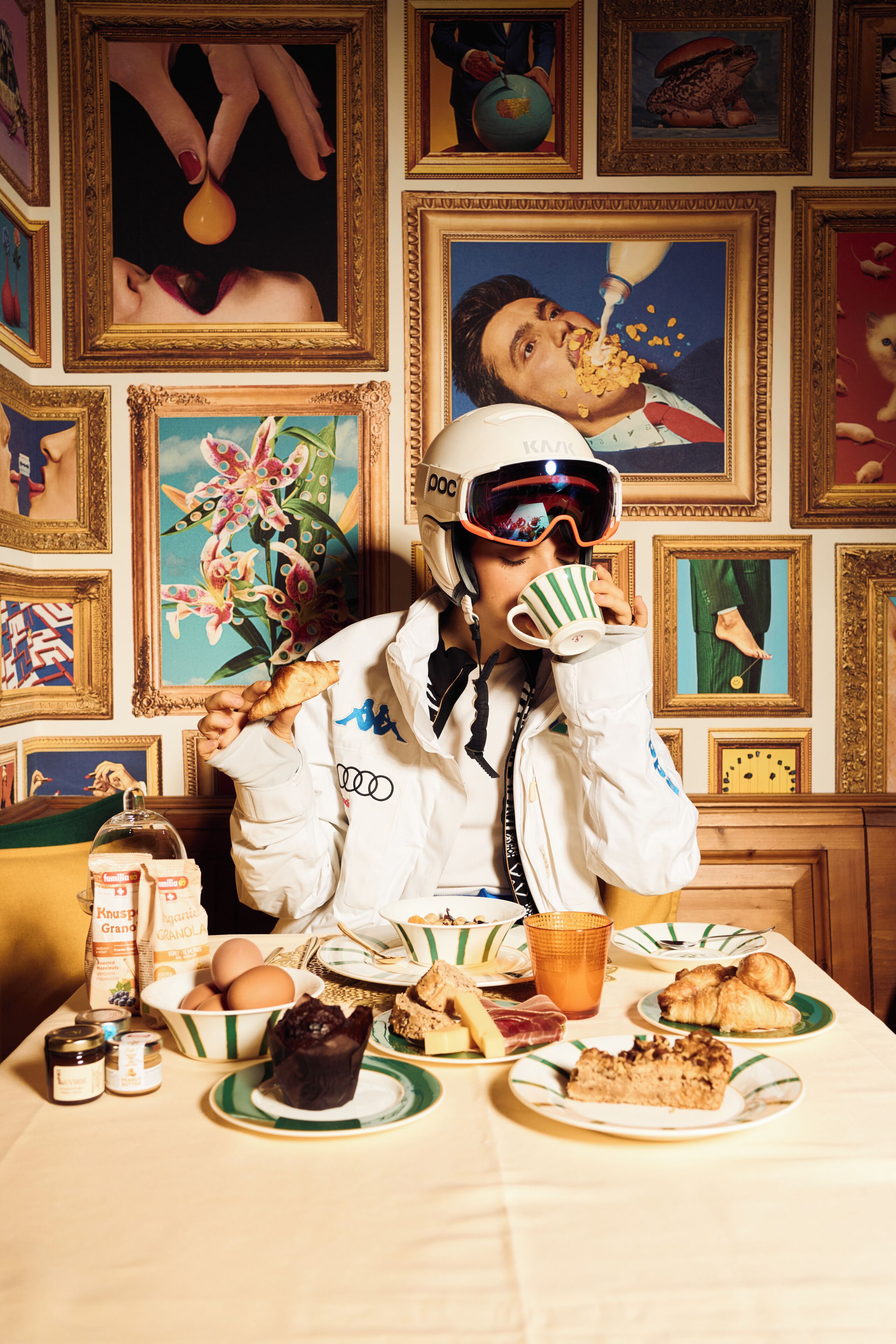 A dining table with food, a person in a white jacket, and various framed artworks on the wall.