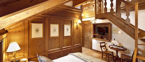 Una camera da letto in legno con un letto, un comodino, una lampada, una sedia, un tavolo e una scala.
