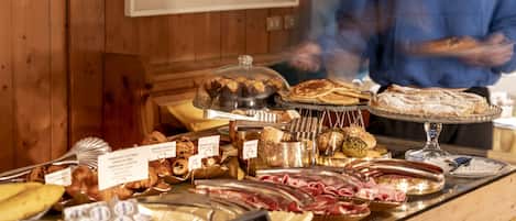 Ein reichhaltiges Buffet mit verschiedenen Speisen, darunter Gebäck, Fleisch und Käse.