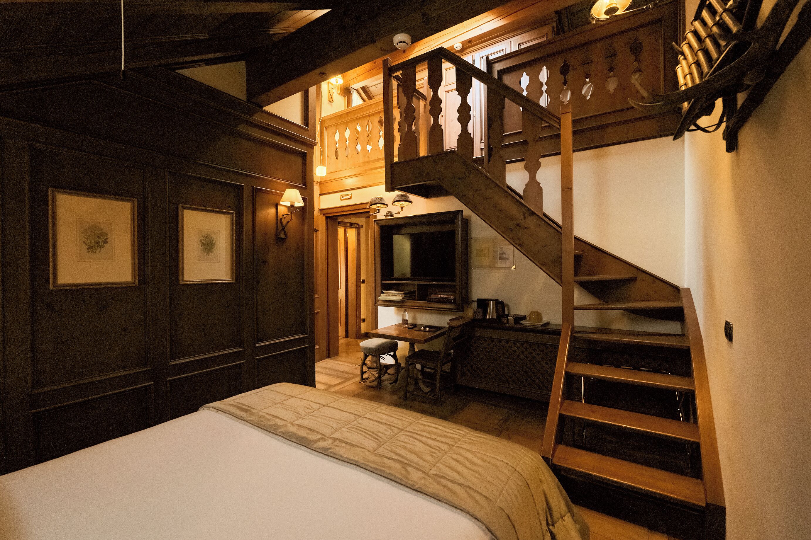 Ein Schlafzimmer mit einer Holztreppe, einem Bett, einem Schreibtisch und einem Stuhl.