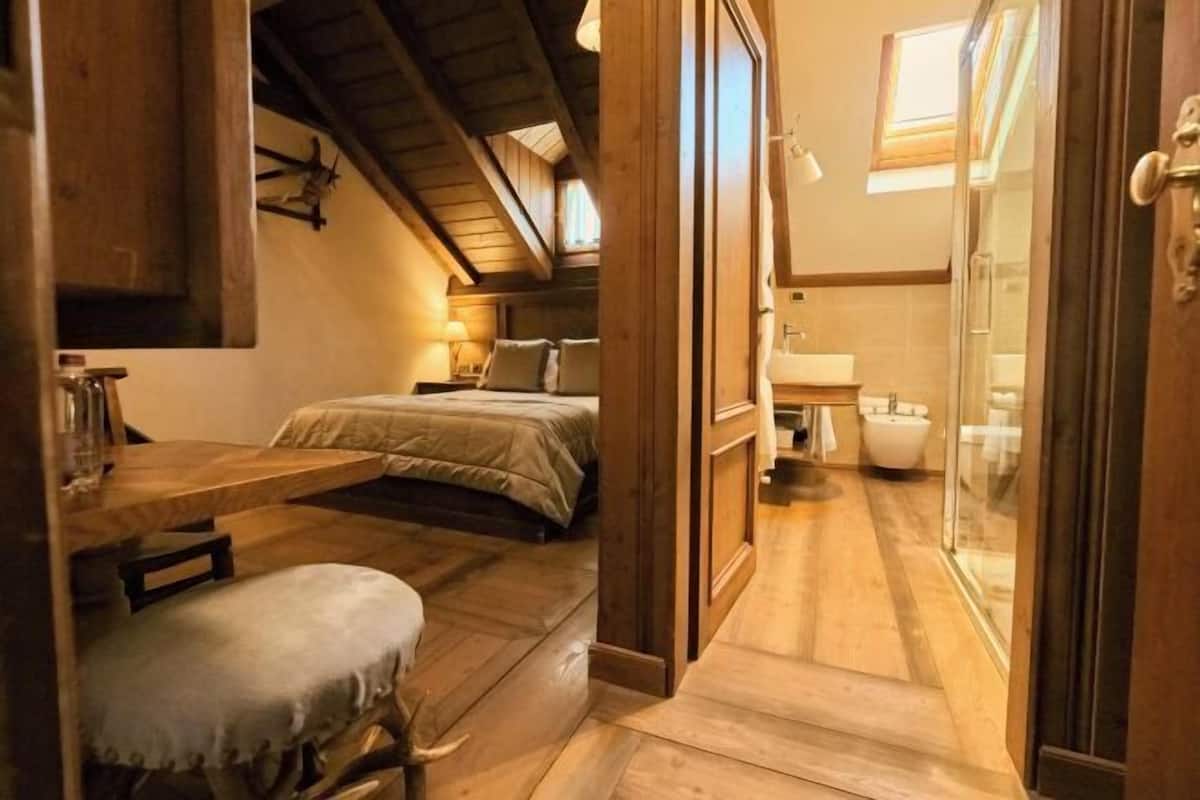 Une chambre à coucher avec un lit, une table de chevet et un petit tabouret.