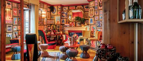 A cozy room with a fireplace, a mirror, and a variety of framed pictures on the walls.