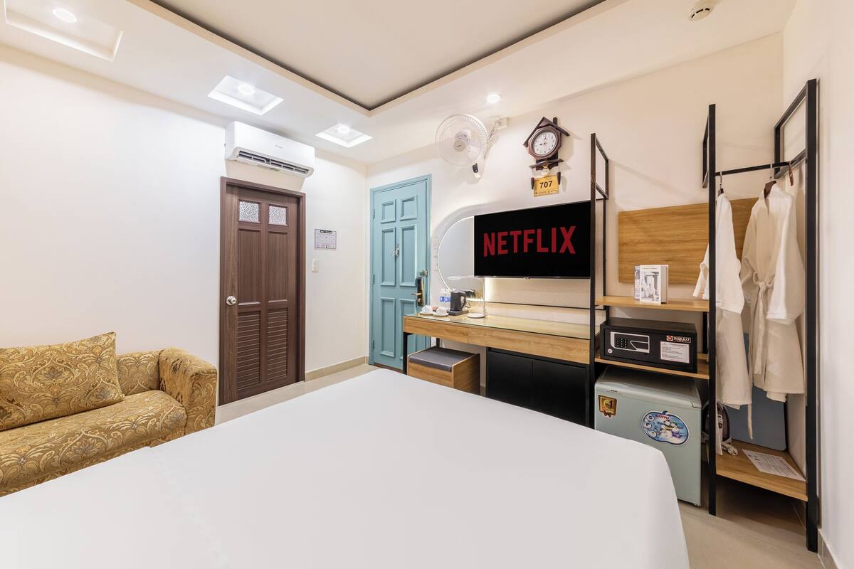 Une chambre d’hôtel avec un lit, un bureau équipé d’un ordinateur, un téléviseur affichant le logo « NETFLIX », une armoire et une porte portant le numéro « 707 ».