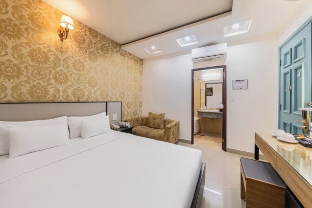 Ein Hotelzimmer mit einem großen Bett, einem Schreibtisch mit Stuhl, einer Wand mit Muster und einer Klimaanlage.