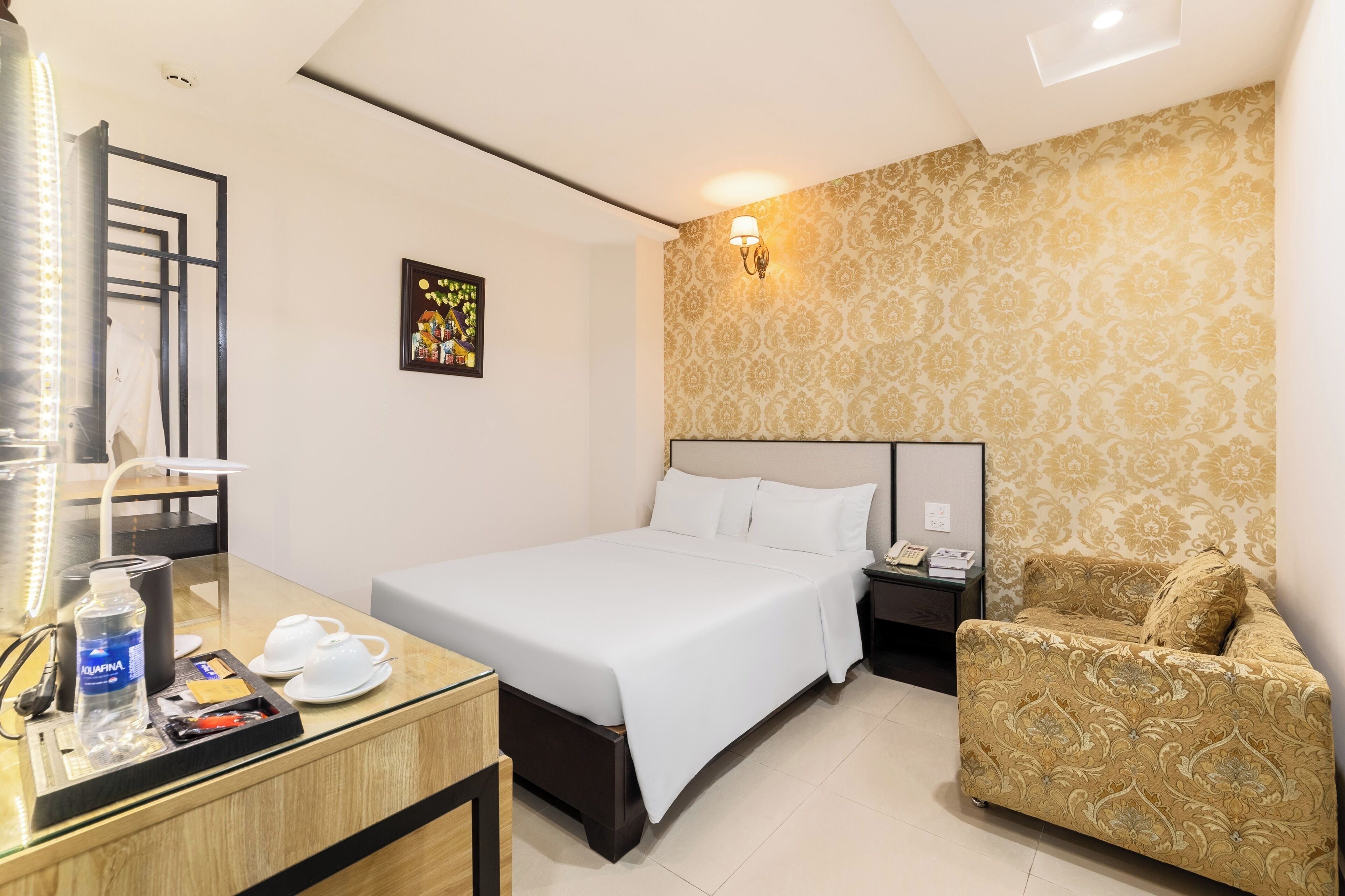Une chambre d’hôtel avec un lit, une table de chevet, une lampe et un mur décoré d’un motif.
