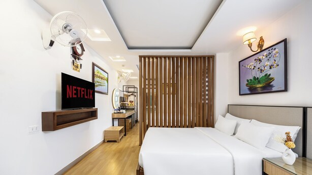 A modern hotel room with a large bed, a TV mounted on the wall, a wooden partition, and a framed artwork above the bed. - A25 Premium Hotel - 29 Bui Thi Xuan (Ho Chi Minh City)