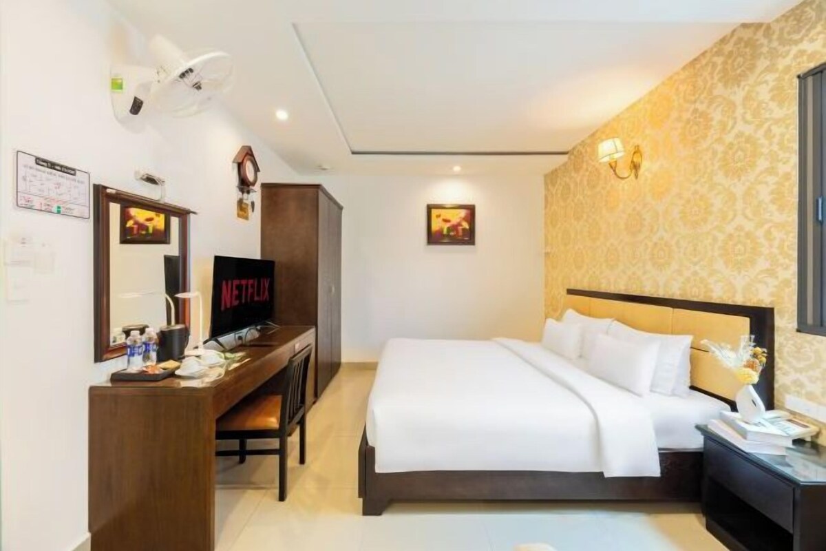 Une chambre d’hôtel équipée d’un lit, d’un bureau avec un ordinateur, d’une télévision et d’une lampe fixée au mur.